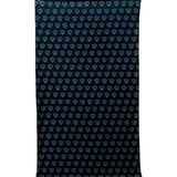 Overhead flat lay image of the back side of a black fleece neck gaiter featuring a repeating dark gray diamond-shield pattern. The gaiter has an adjustable drawstring at the top and is placed on a white background.