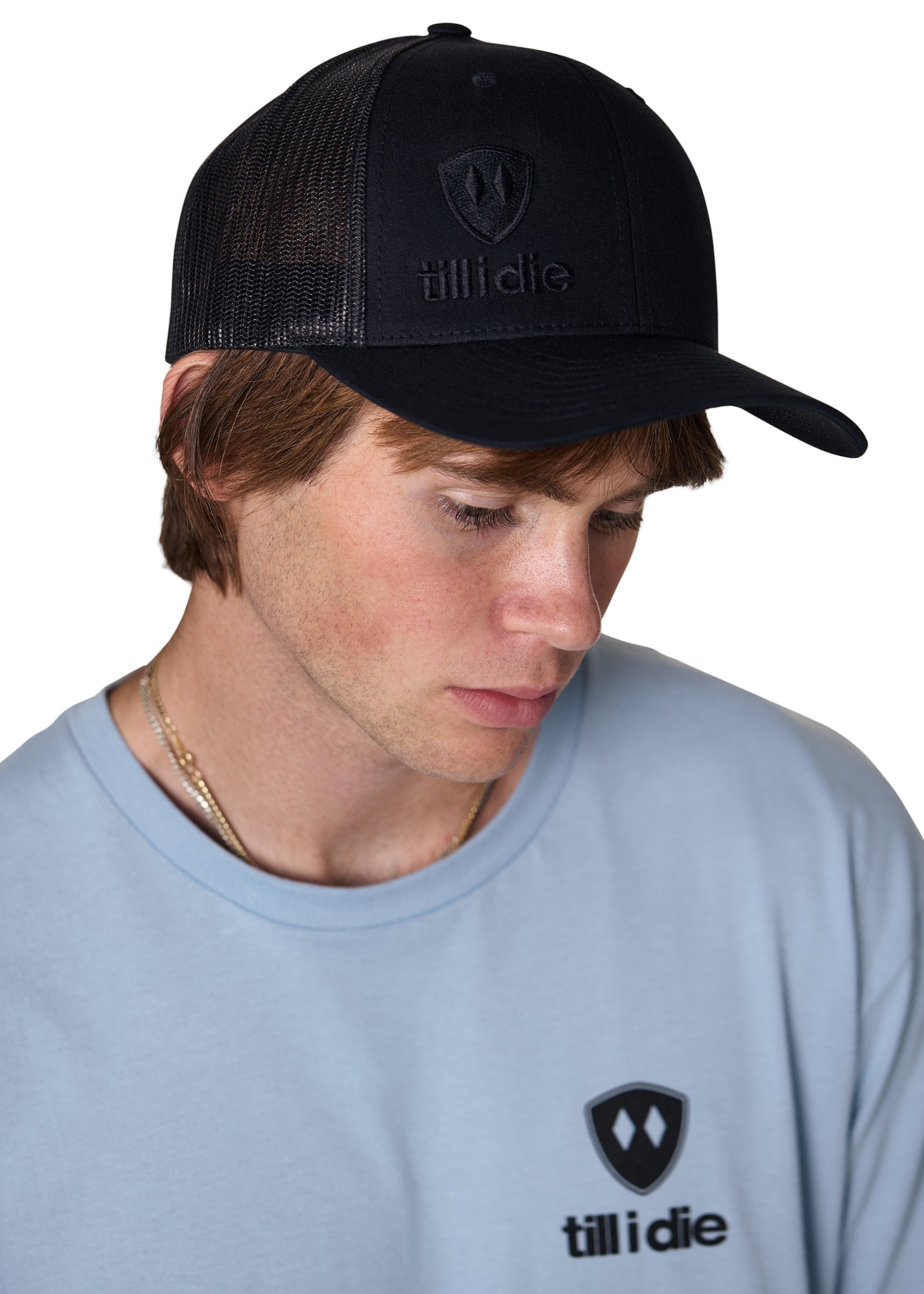 Male model wearing the Till I Die Black-on-Black Trucker Hat, showing the front puff embroidered logo and mesh back.