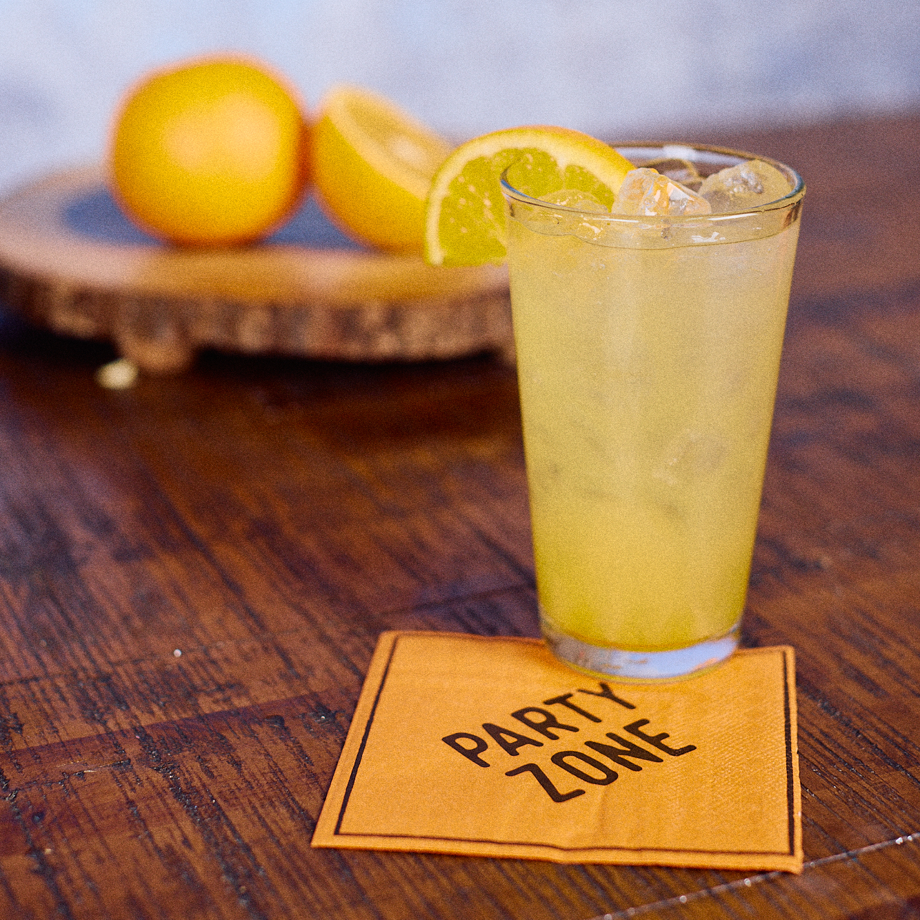 Tabletop image of a Manmosa cocktail in a pint glass sitting on top of a party zone cocktail napkin