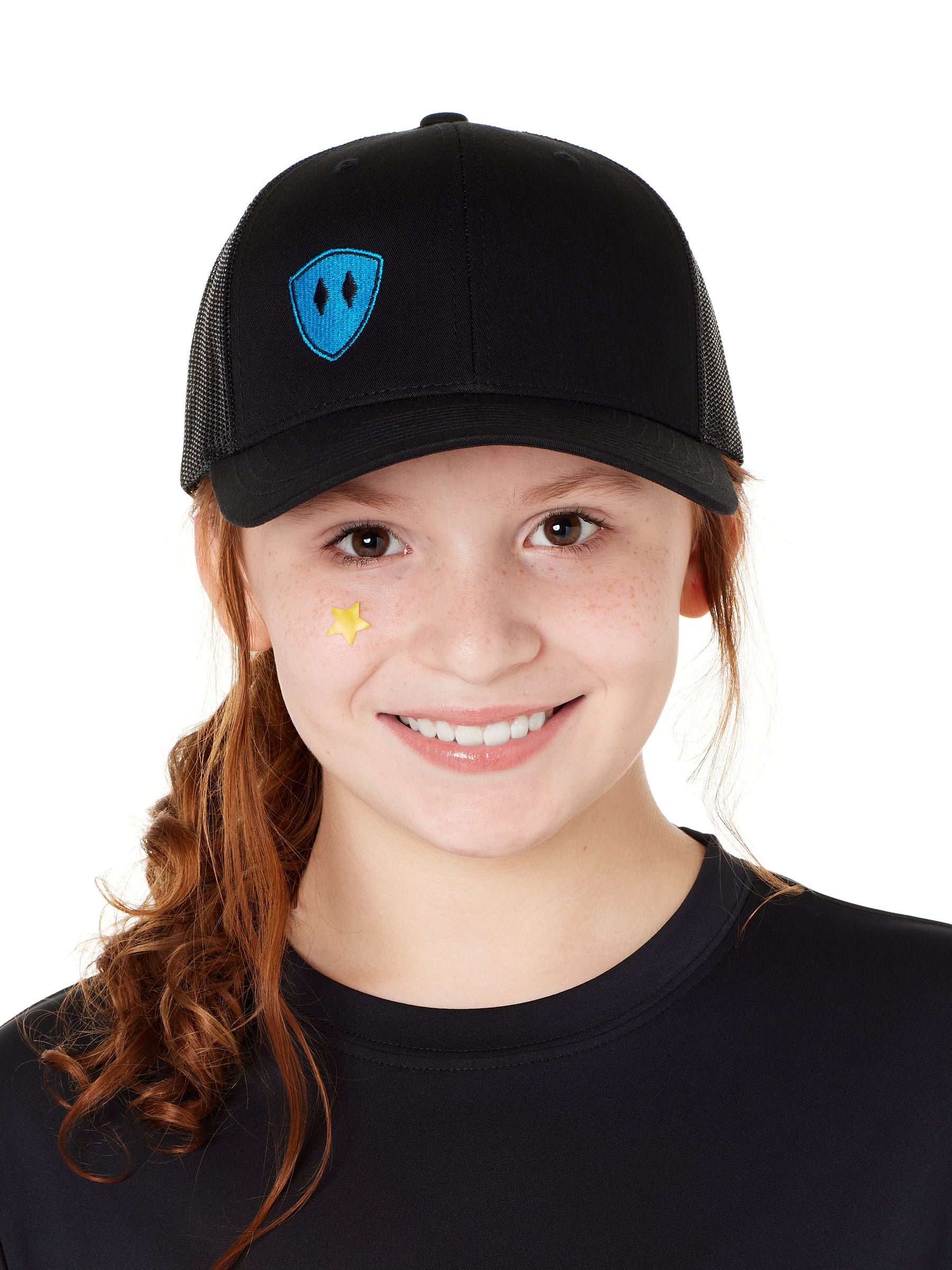 Front view of a youth wearing a black classic trucker hat with a blue embroidered double diamond shield on the bottom right panel