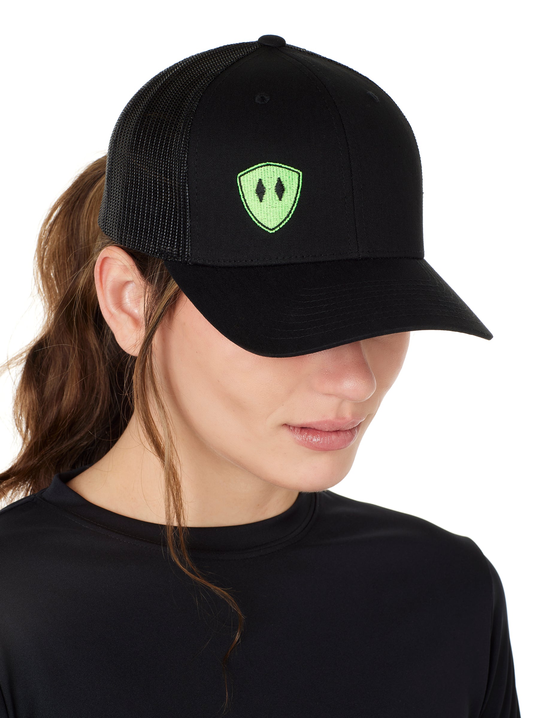 Front view of a female wearing a black classic trucker hat with a lime embroidered double diamond shield on the bottom right panel
