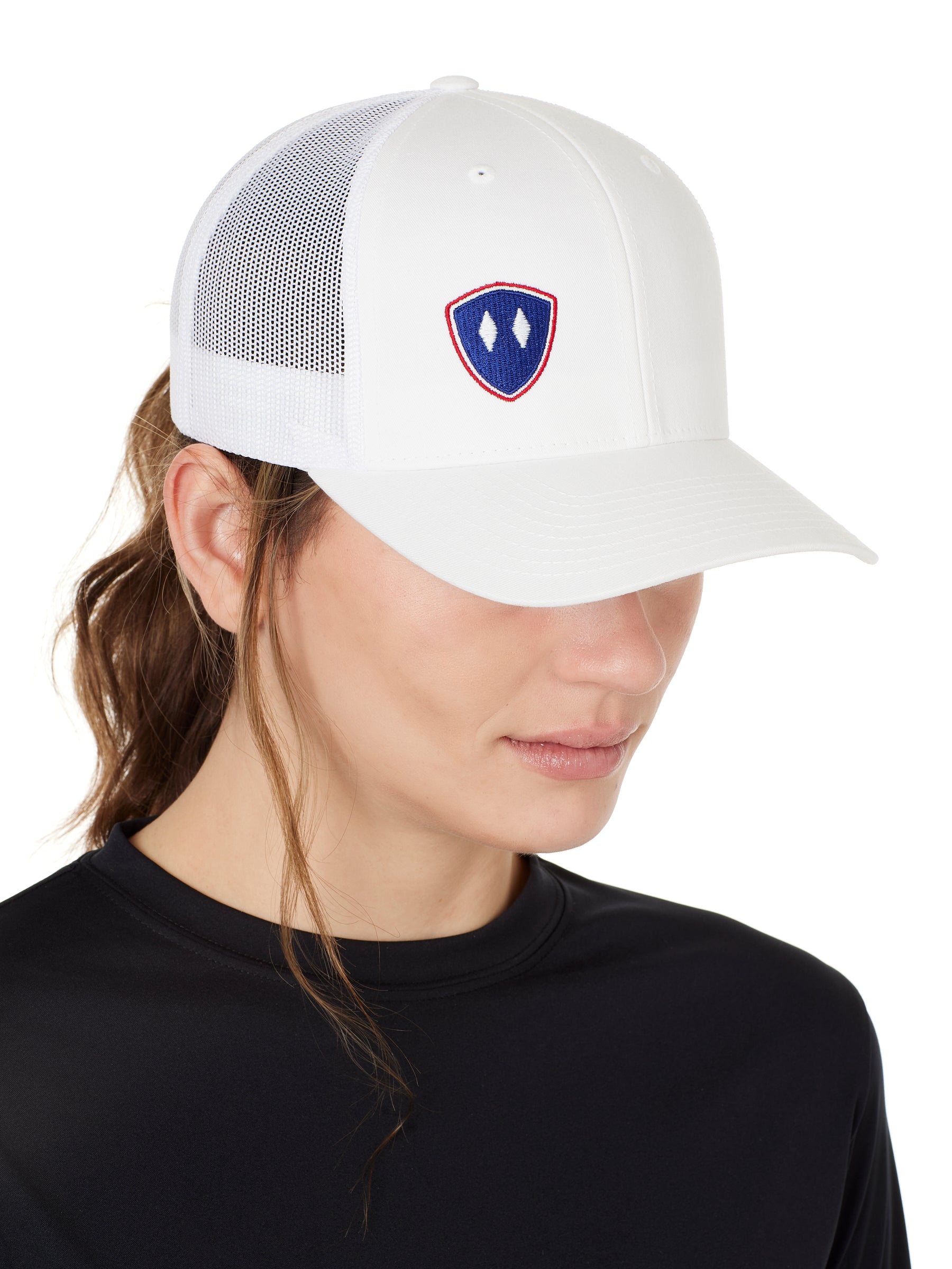 Front view of a female wearing a white classic trucker hat with a blue and red embroidered double diamond shield on the bottom right panel