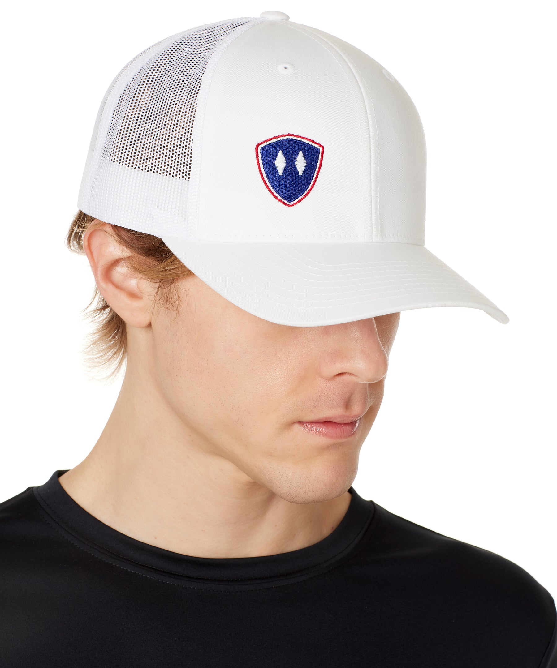 Front view of a male wearing a white classic trucker hat with a blue and red embroidered double diamond shield on the bottom right panel