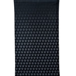 Overhead flat lay image of the back side of a black neck gaiter featuring a repeating dark gray diamond-shield pattern. The gaiter is placed on a white background.