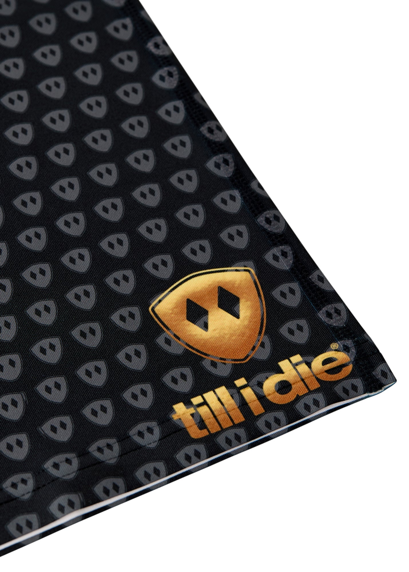 Close-up flat lay showing the gold Till I Die logo printed near the bottom right hem of the neck gaiter.
