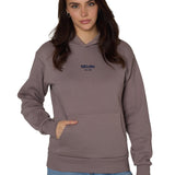 Female model in Ski Till I Die Rhinestone hoodie in Shiitake brown, front view with Till I Die and Established date 2010 in Sapphire metallic embroidery, Winter 2025 collection