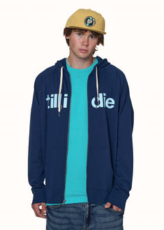 male model wearing a navy zip hoodie with "till i die" in light blue across the front. Paired with a teal tee and sunset yellow surf cap.