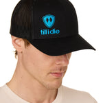 Front view of a male model wearing a black classic trucker hat, featuring a blue embroidered Till I Die logo on the lower right front panel.