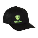 Front view of a black classic trucker hat, featuring a green embroidered Till I Die logo with double black diamonds and a green shield on the lower right front panel on a white background.
