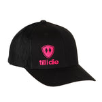 Front view of a black classic trucker hat, featuring a hot pink embroidered Till I Die logo with double black diamonds and a hot pink shield on the lower right front panel on a white background.