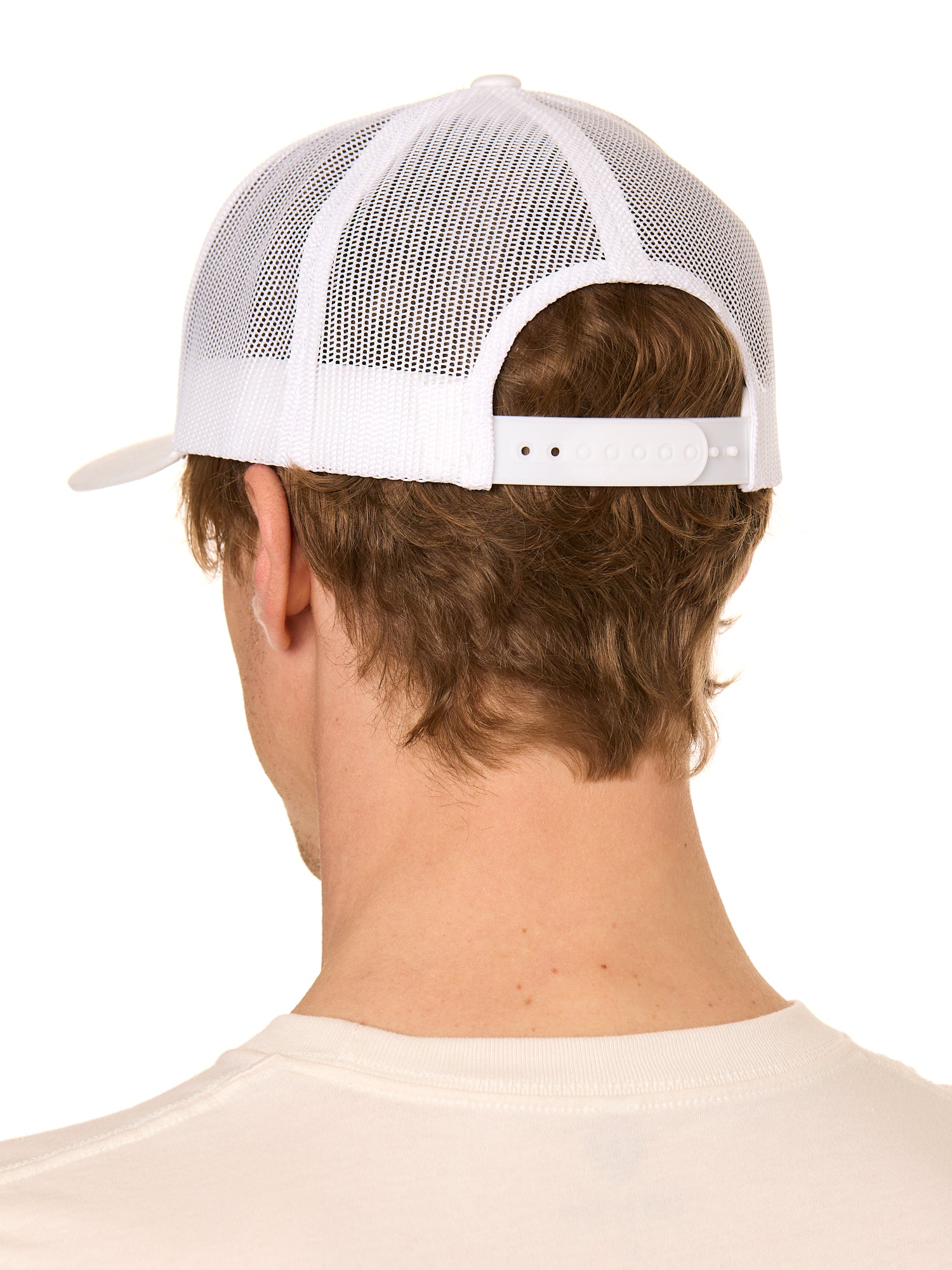 Back view of a male model wearing a classic white trucker hat featuring the mesh back panels and matching white snapback closure