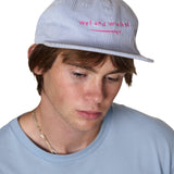 Model wearing the Wet and Wrecked corduroy surf hat with pink embroidery of a surf board and the words "wet and wrecked'