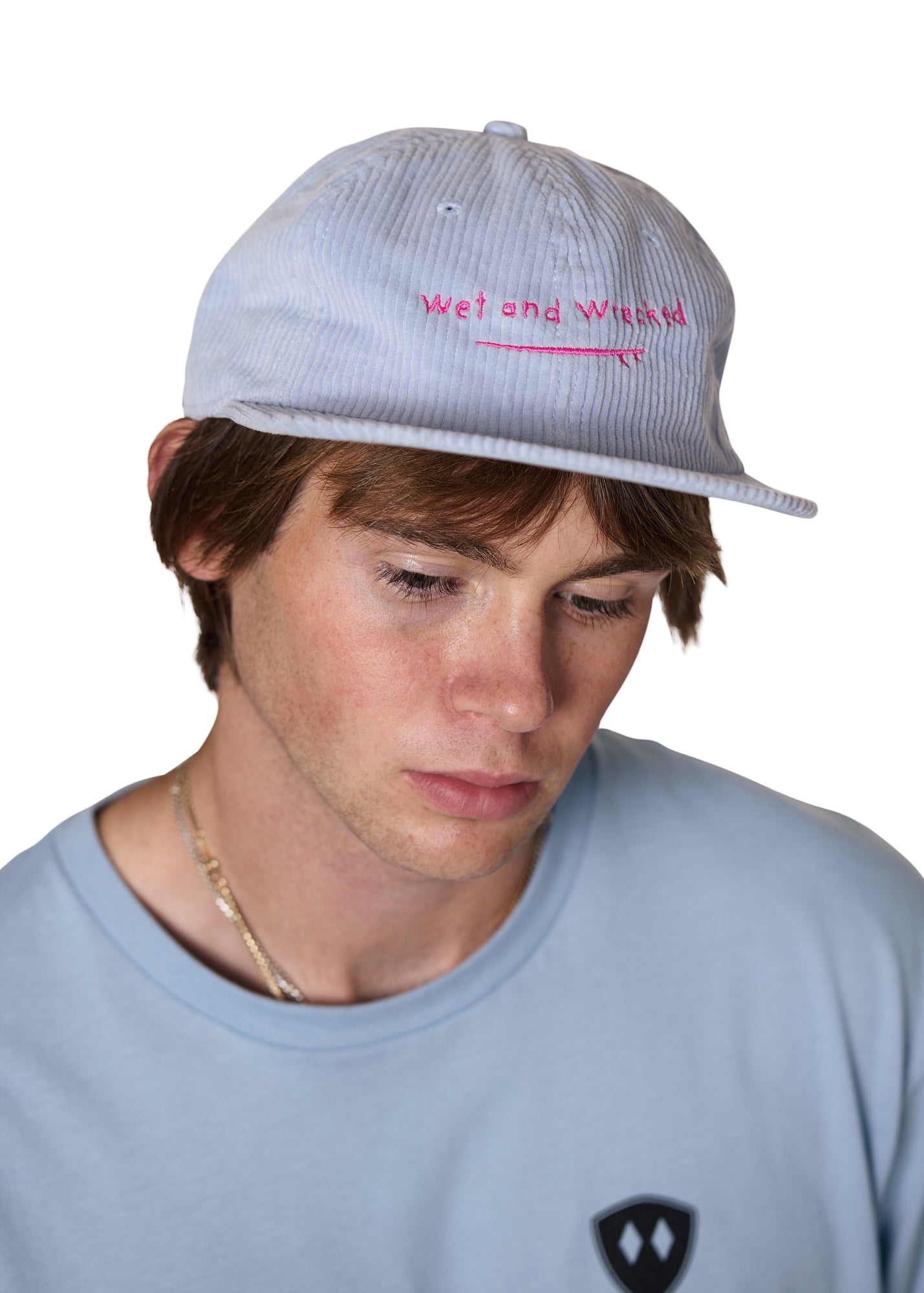 Model wearing the Wet and Wrecked corduroy surf hat with pink embroidery of a surf board and the words "wet and wrecked'