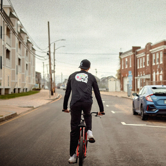 Person riding a bicycle on a city street with a car parked nearby